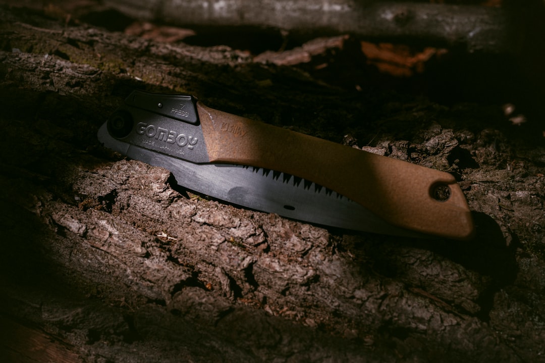 A folding pruning saw resting on a wooden garden bench